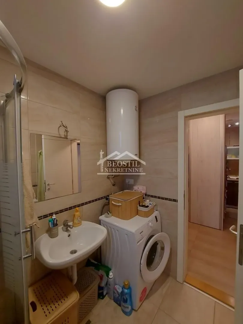 Bathroom equipped with a sink, shower cabin, and washing machine.