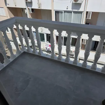 View from the tiled balcony with a white balustrade towards the building across. - image 10