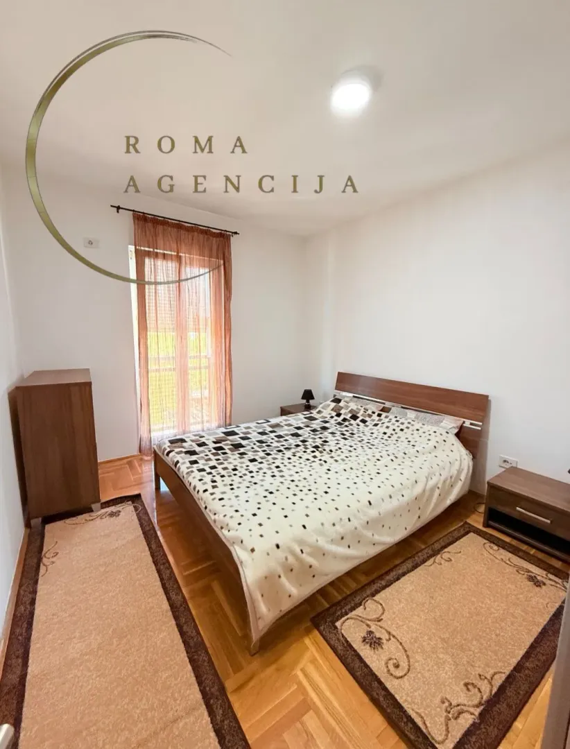 Furnished bedroom with a double bed, nightstand, and balcony access.
