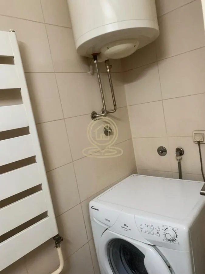 Kupatilo sa veš mašinom i bojlerom na zidu.