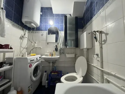 Kupatilo opremljeno sanitarijama, mašinom za veš i plavim zidnim pločicama. - image 8