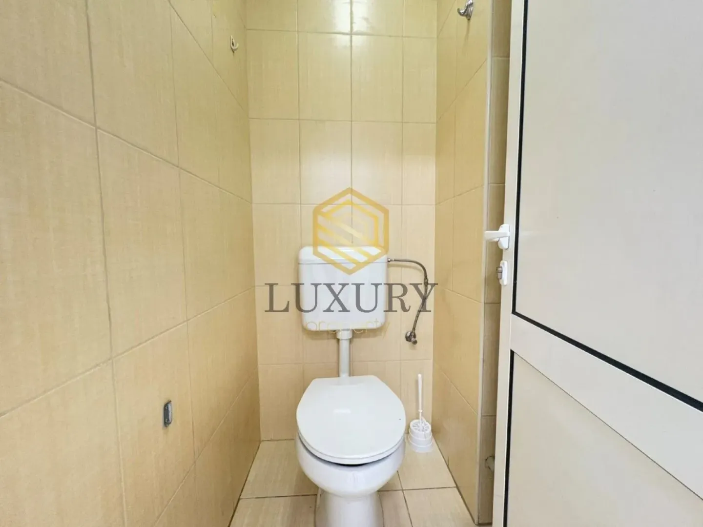 Smaller bathroom tiled with ceramic tiles featuring a toilet.