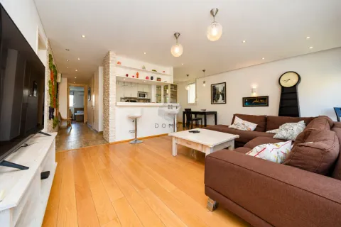 Spacious living room with a sofa, TV, and a view of the kitchen and bar. - image 13