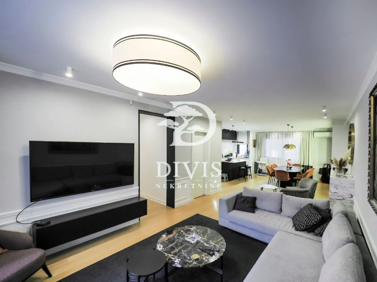 Spacious living room with seating area and TV, connected to the dining area and kitchen.