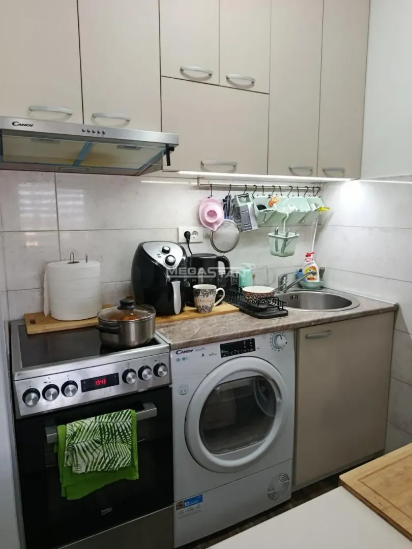 Compact equipped kitchen with a stove, sink, and integrated washing machine.