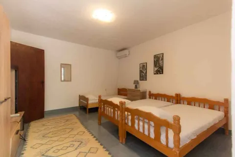 Prostrana spavaća soba sa nekoliko drvenih kreveta i tepihom. - image 9