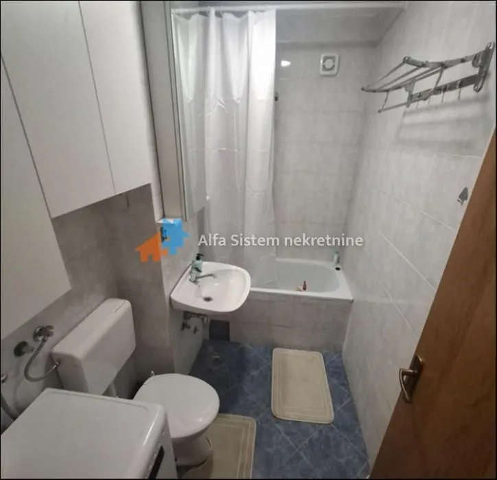 Smaller bathroom with a bathtub, washbasin, toilet, and washing machine.