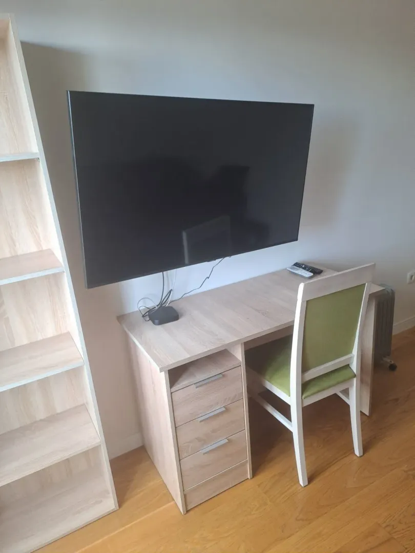 Radni kutak sa stolom, stolicom i zidnim televizorom.