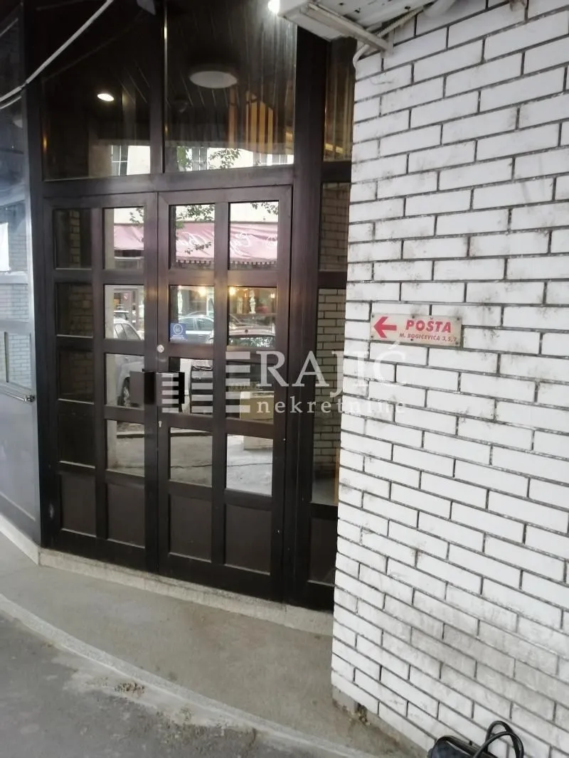 Entrance to a commercial space with dark wooden joinery and white brick on the wall.