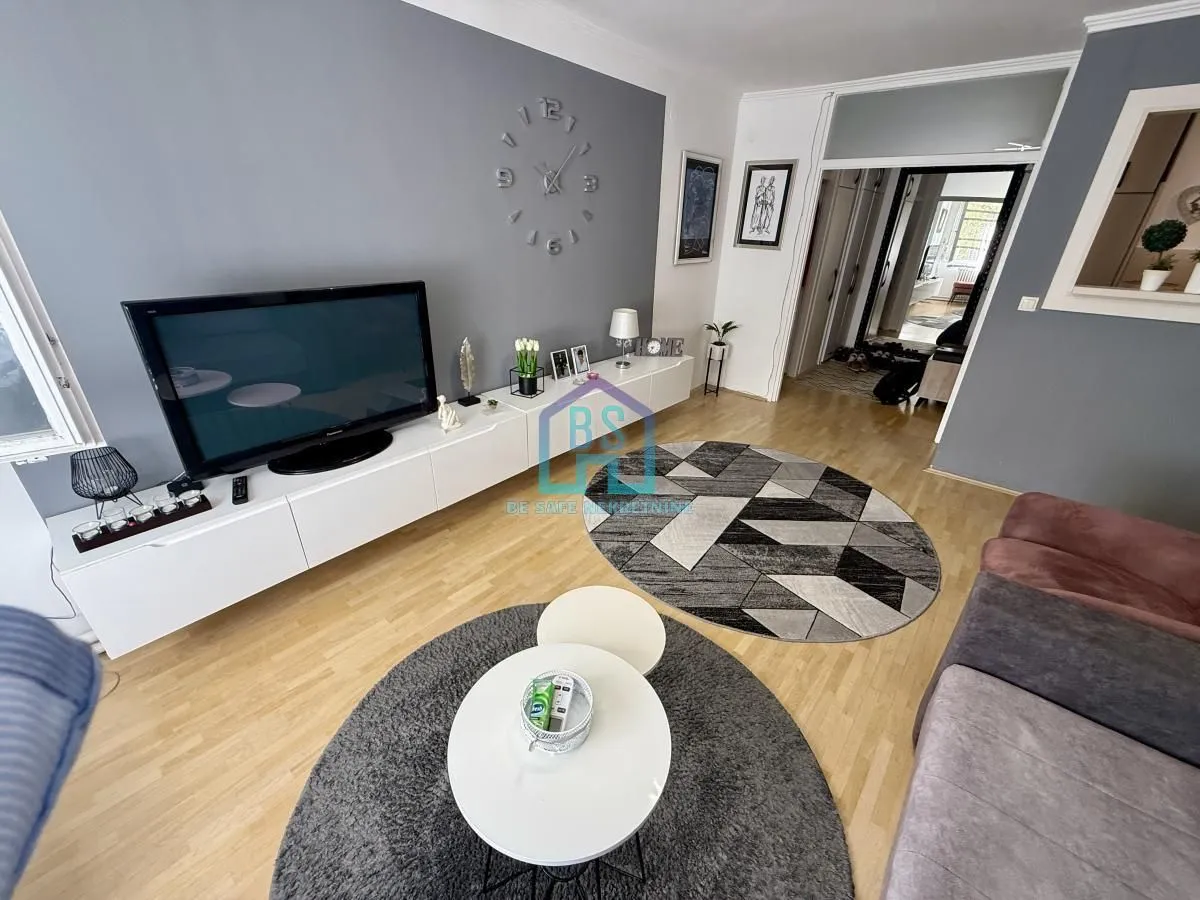 Dnevna soba sa garniturom, TV-om i okruglim stočićima.