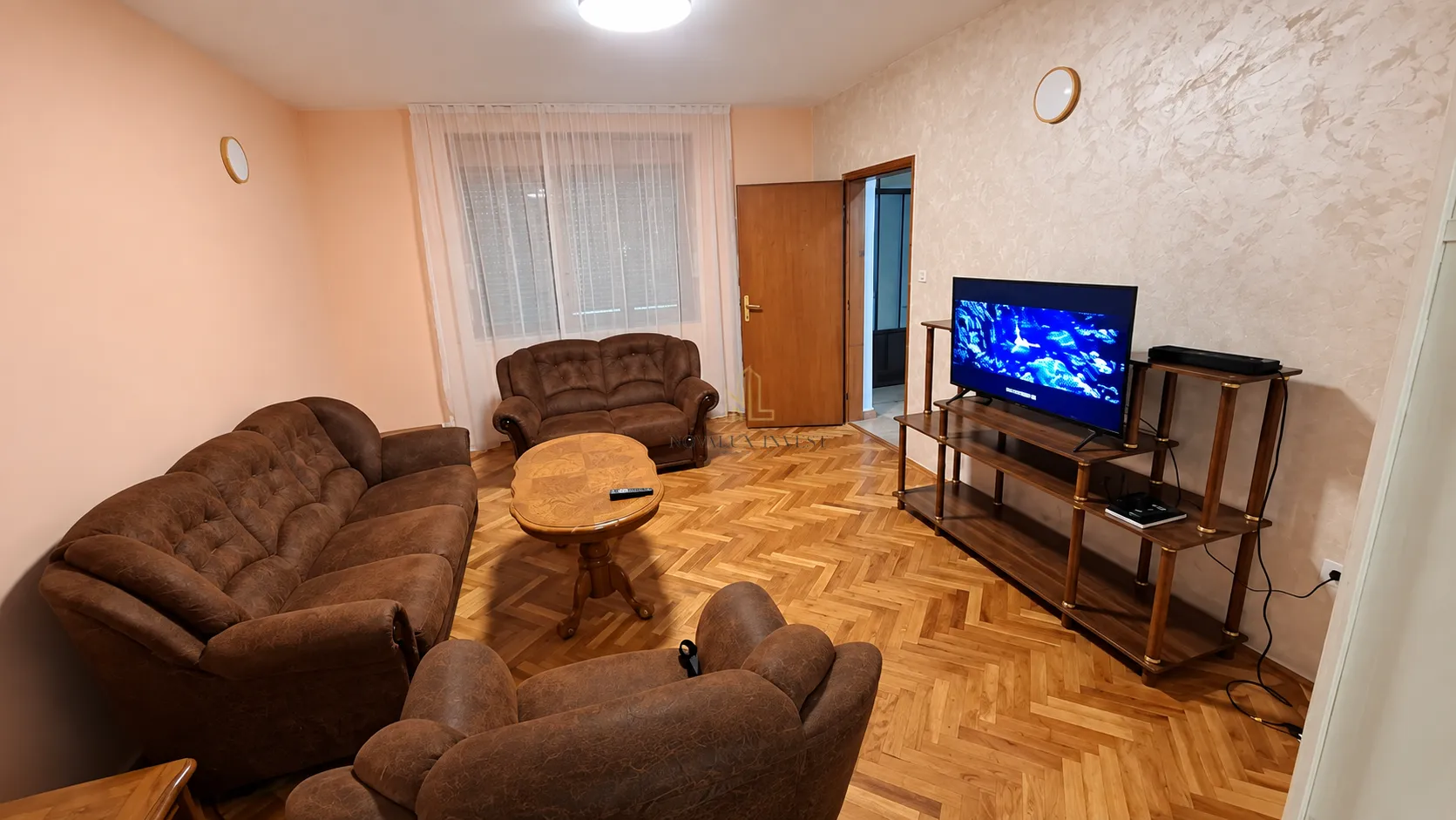 Dnevna soba sa garniturom, drvenim stočićem i televizorom.