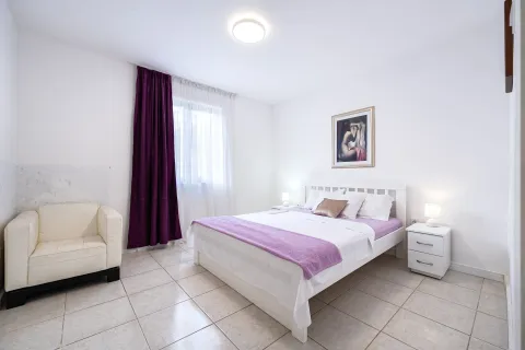 Spacious bedroom featuring a double bed, an armchair, and a window with purple curtains. - image 5
