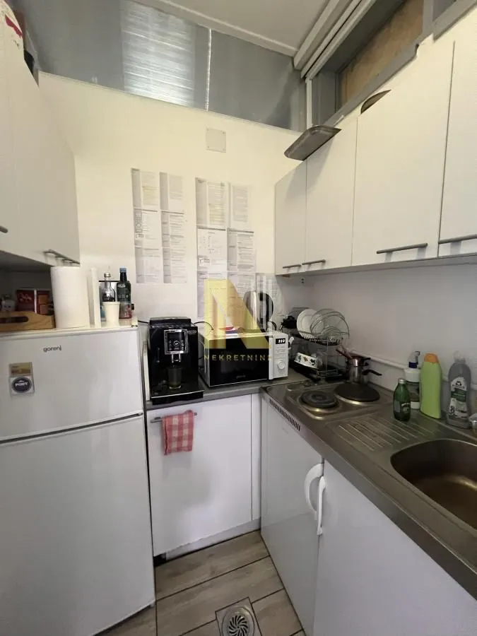 Small equipped kitchen with white cabinetry and a refrigerator.