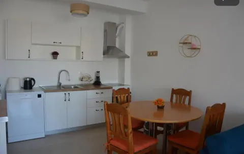 Manja bijela kuhinja sa trpezarijskim stolom i drvenim stolicama. - image 5