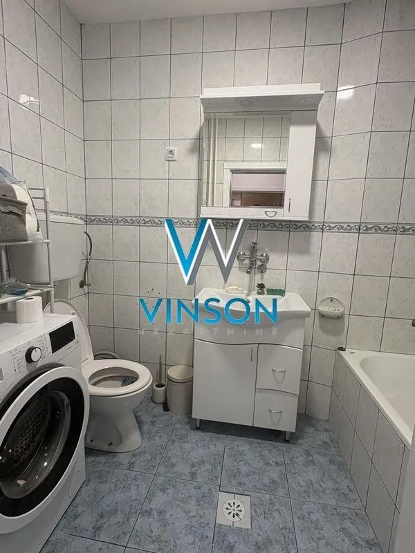 Kupatilo opremljeno sanitarijama, umivaonikom sa ormarićem, ogledalom, kadom i veš mašinom.