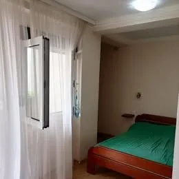 Bedroom with a double bed and a window with white curtains.