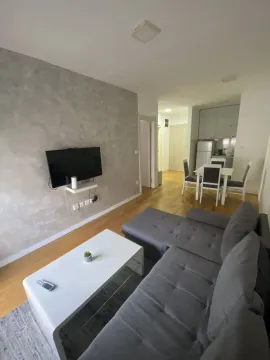Bright living room featuring a gray sectional sofa, coffee table, and background dining area. - image 4