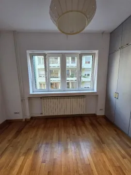 Prazna soba sa parketom, ugrađenim plakarom i prozorom sa pogledom na susednu zgradu. - image 10