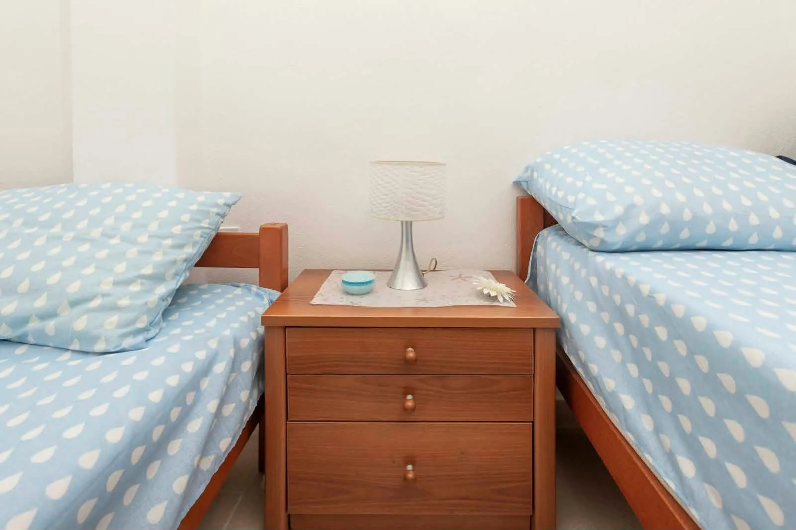 Bedroom with two wooden beds and a nightstand between them.