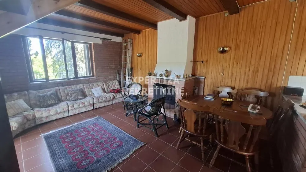 Spacious living room with a fireplace, wooden paneling, and a dining area.