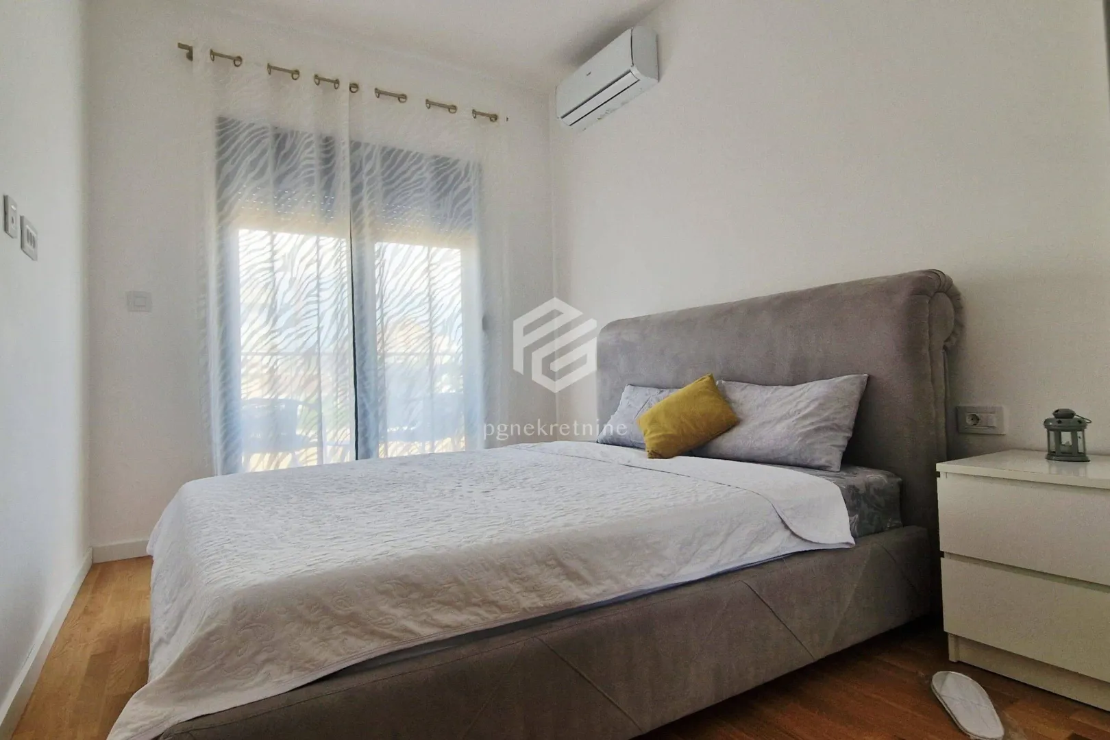Bedroom with a double bed, bedside table, and air conditioning unit.