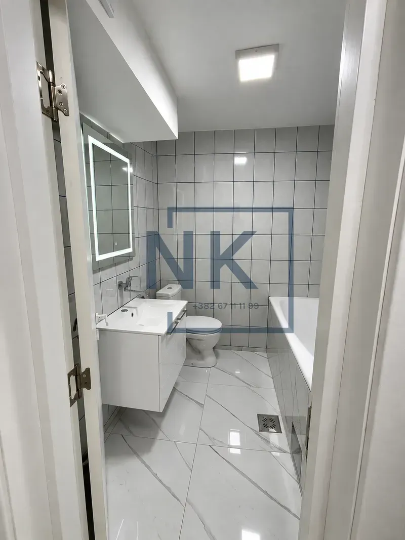 Potpuno opremljeno kupatilo sa kadom, umivaonikom i osvijetljenim ogledalom.