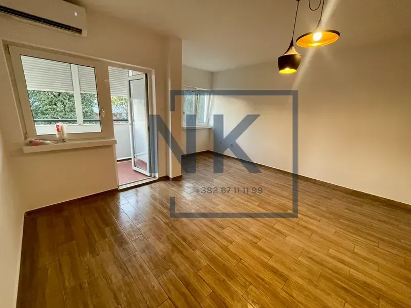 Empty living room with wood-look flooring, air conditioning and access to the balcony.