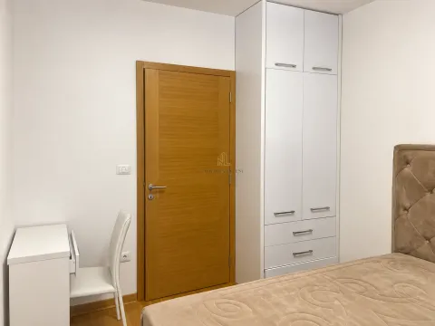 Spavaća soba sa krevetom, bijelim garderoberom, radnim stolom i drvenim vratima. - image 7