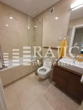 Modernly equipped bathroom with a bathtub, shower screen, and sink. - image 3