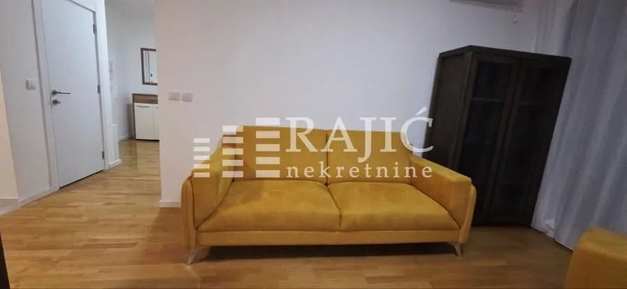 Living room with a yellow sofa and parquet flooring.