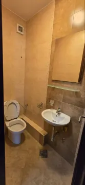 Manje kupatilo obloženo bež pločicama sa wc šoljom, umivaonikom i ogledalom. - image 13