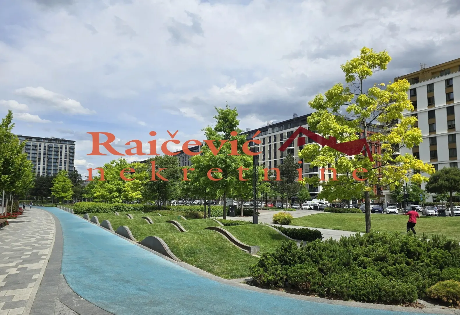 Landscaped courtyard with a pathway and greenery in front of residential buildings.