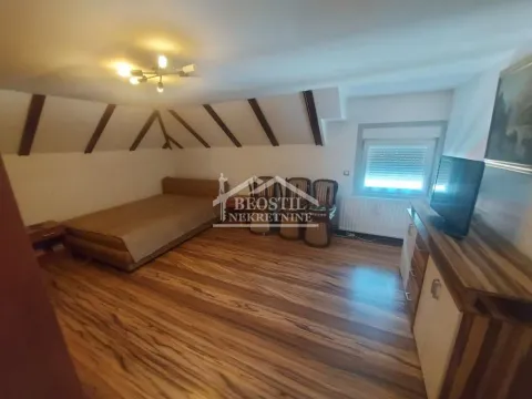 Nameštena spavaća soba sa kosim plafonom i drvenim gredama. - image 4