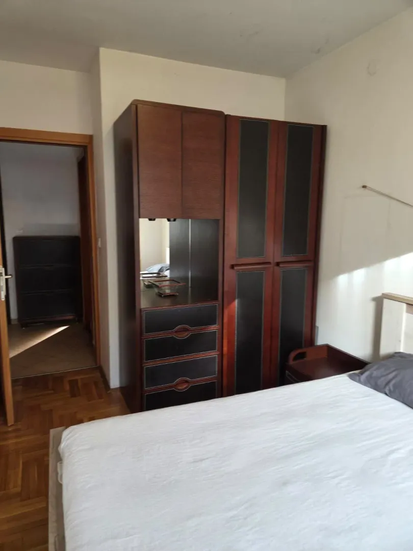 Namještena spavaća soba sa velikim bračnim krevetom i garderoberom.