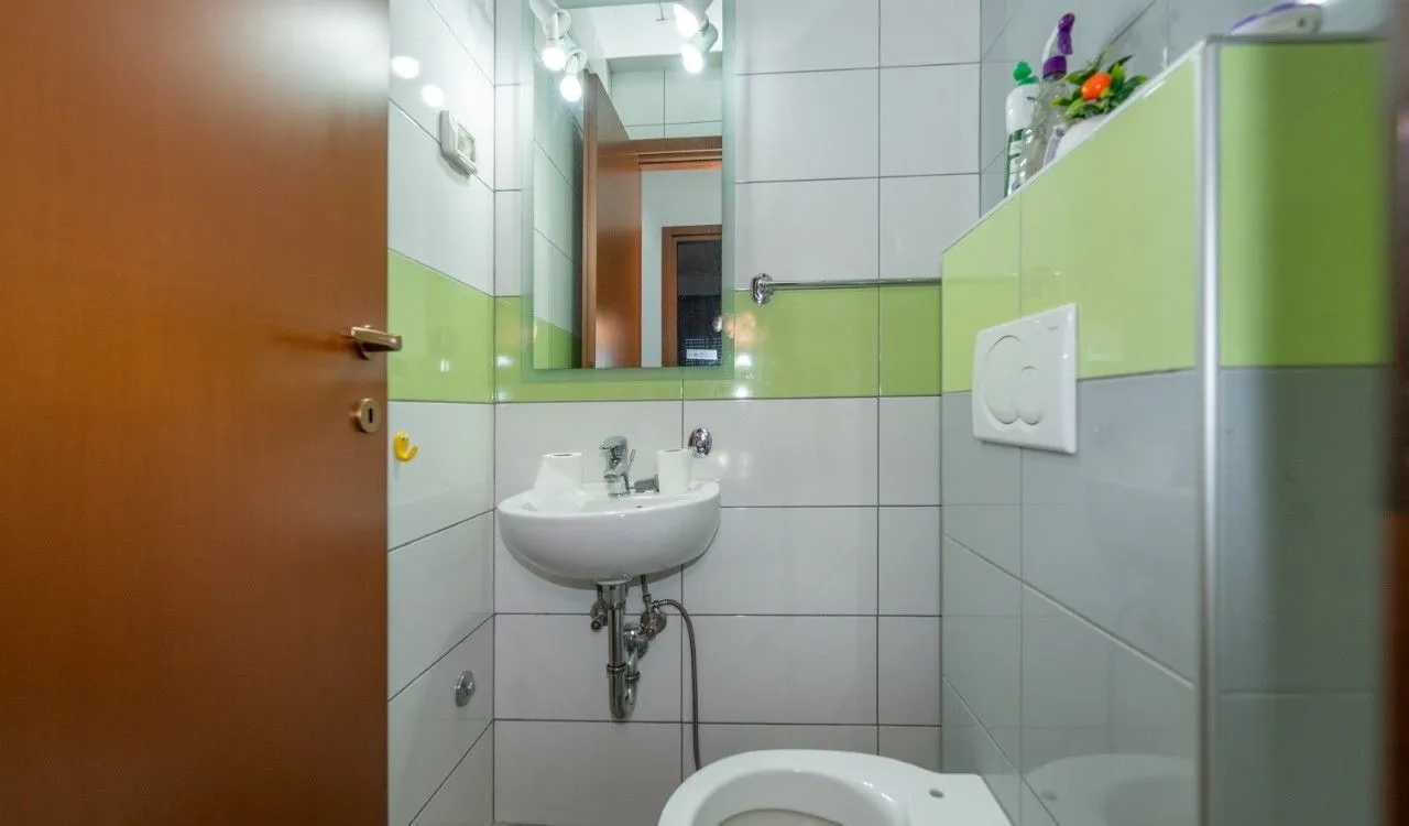 Manje kupatilo sa umivaonikom, ogledalom i WC šoljom.