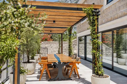 Covered terrace with dining table and greenery. - image 16