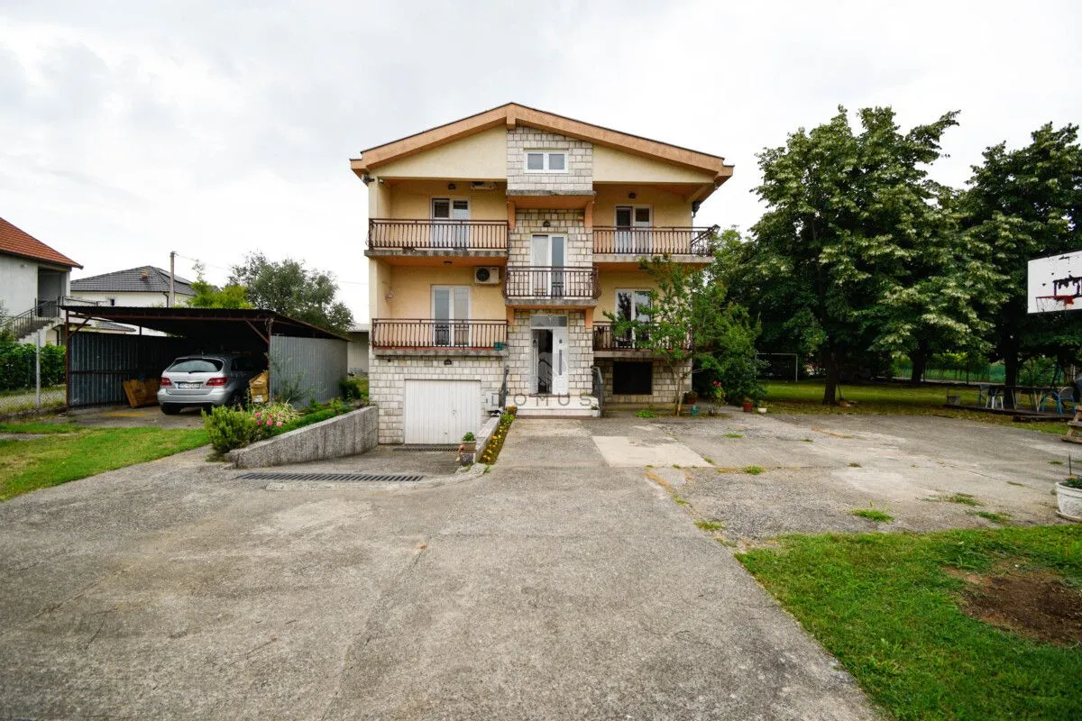 Front view of the house with a yard, balconies, and a garage.