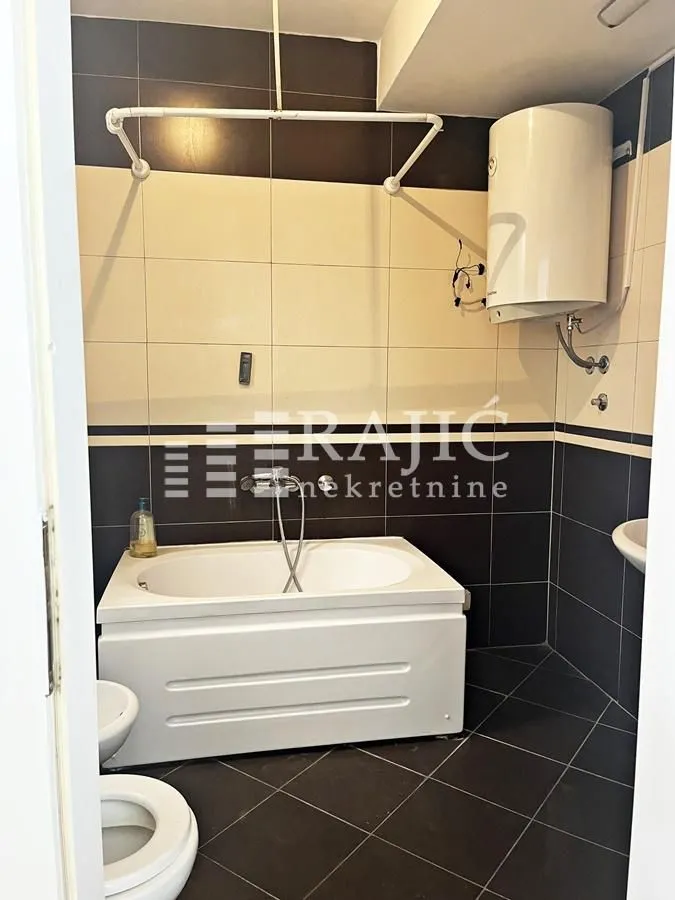 Smaller bathroom with a bathtub and water heater.