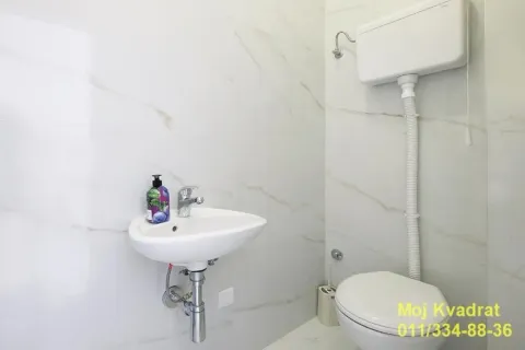 Small bathroom with a sink and toilet tiled with light-colored tiles. - image 11