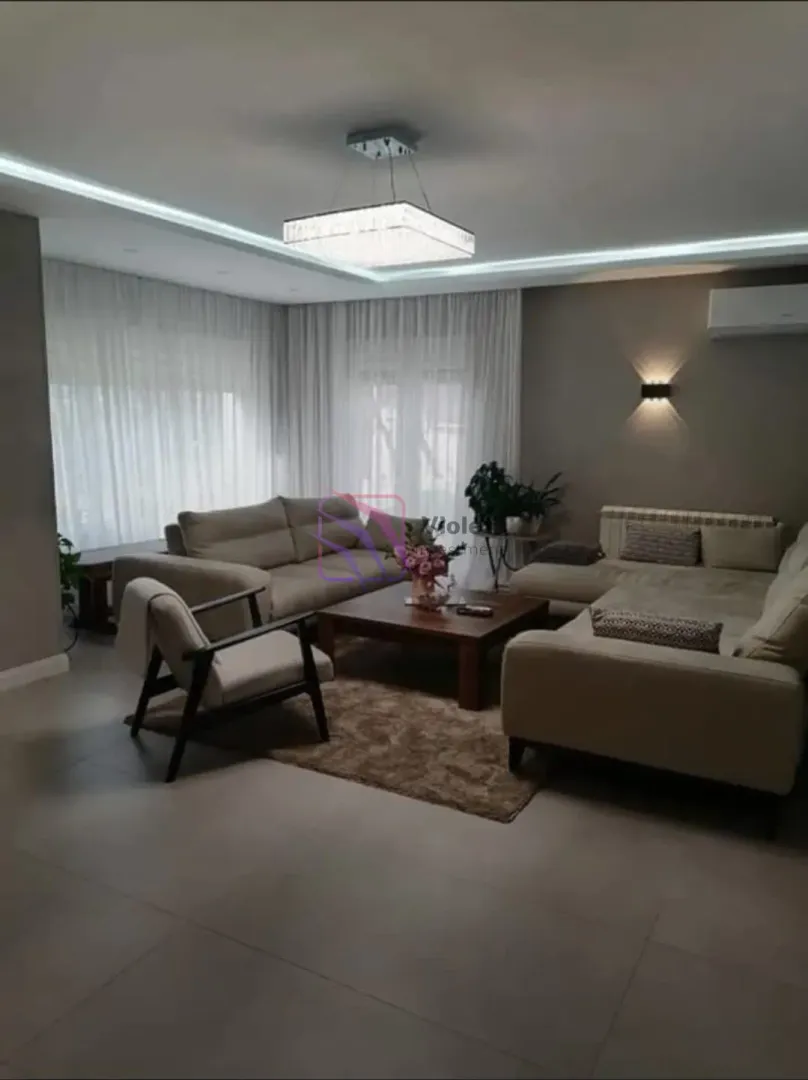Spacious living room with seating furniture, coffee table, and modern lighting.