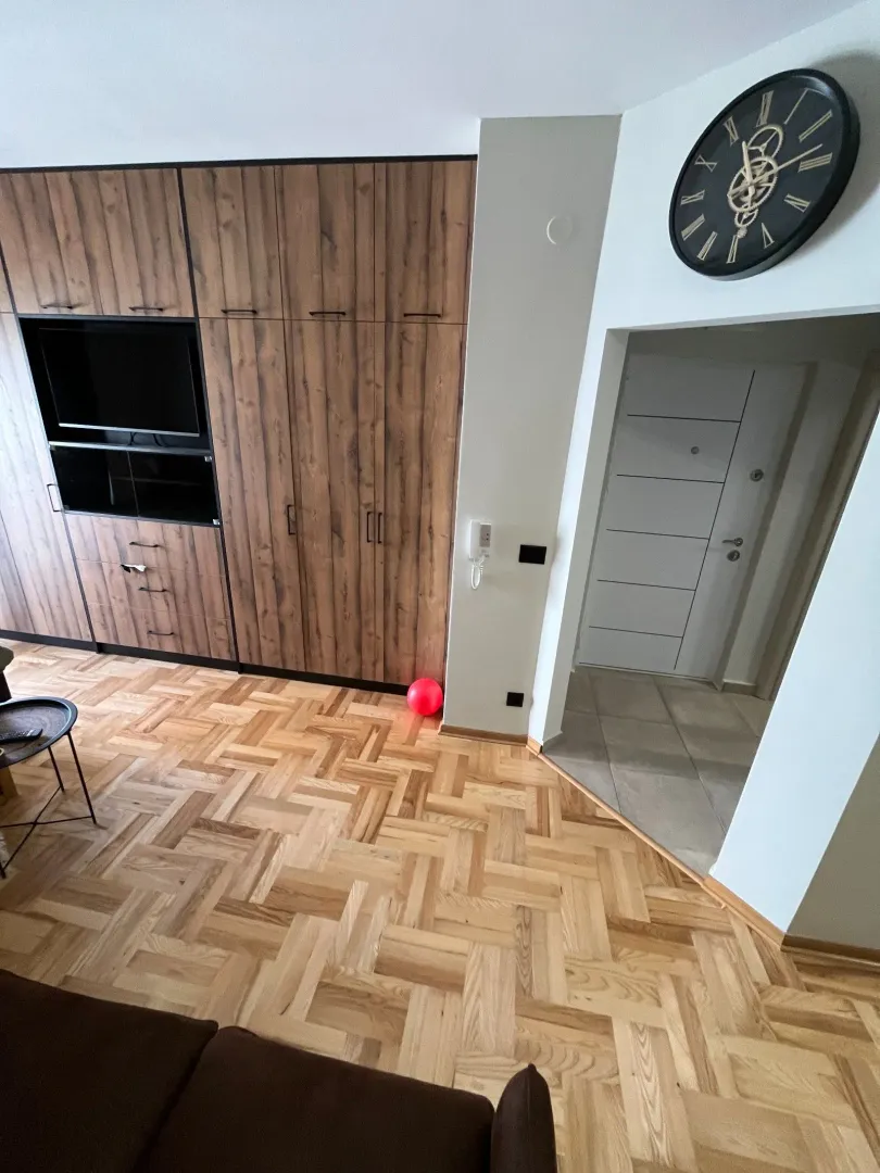 Dnevna soba sa drvenim namještajem, parketom i ulaznim hodnikom.