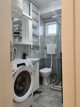 Pogled na moderno uređeno kupatilo sa veš mašinom i tuš kabinom. - image 9