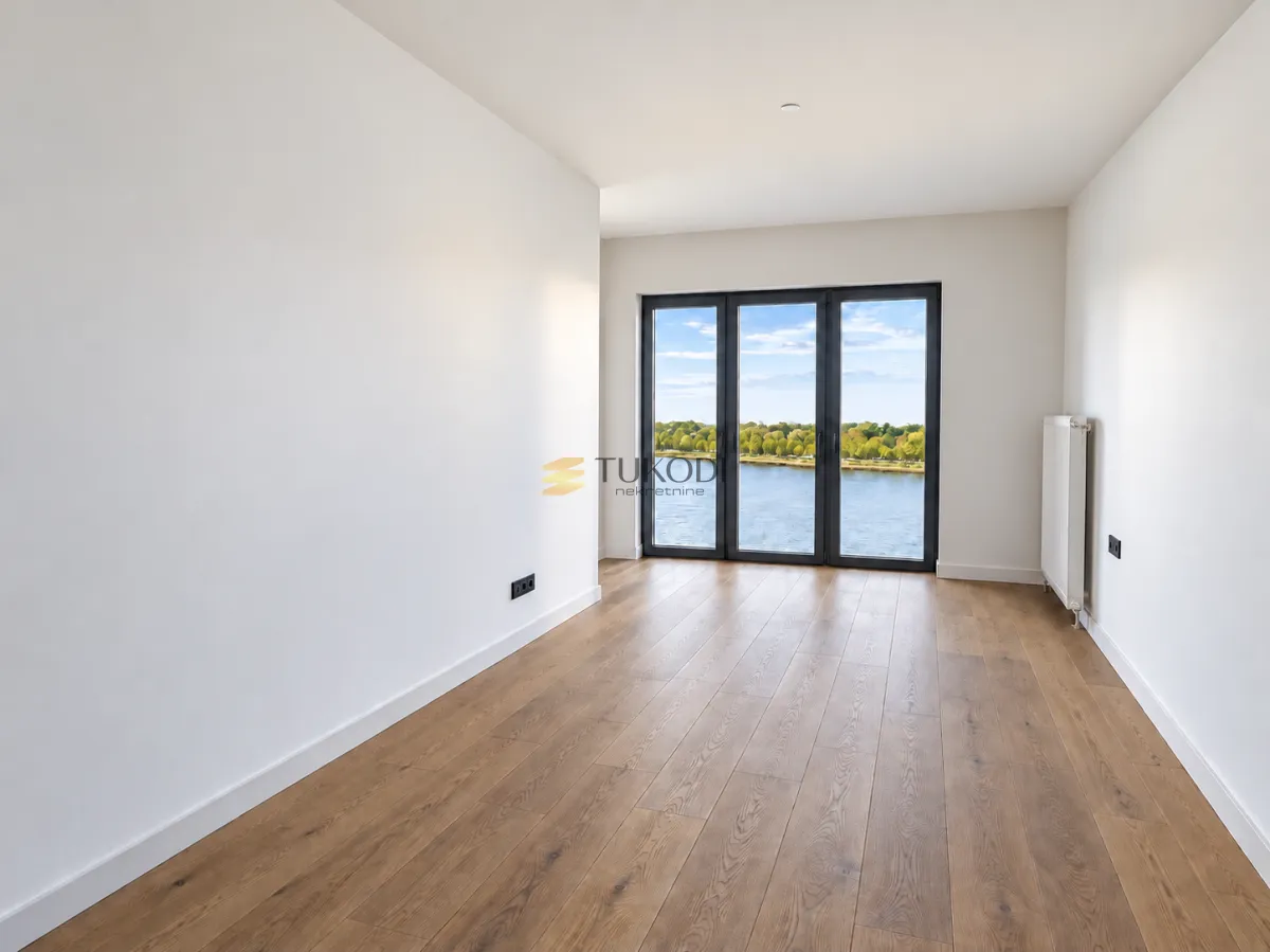 Empty bright room with wooden flooring and a river view.