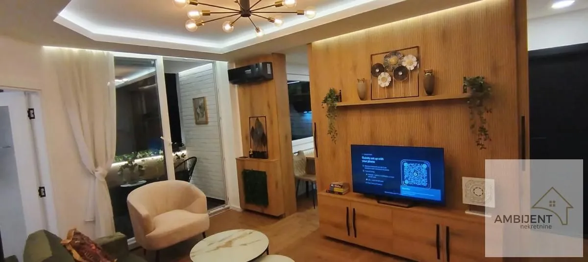 Living room with a wooden wall panel, TV, and access to the terrace.
