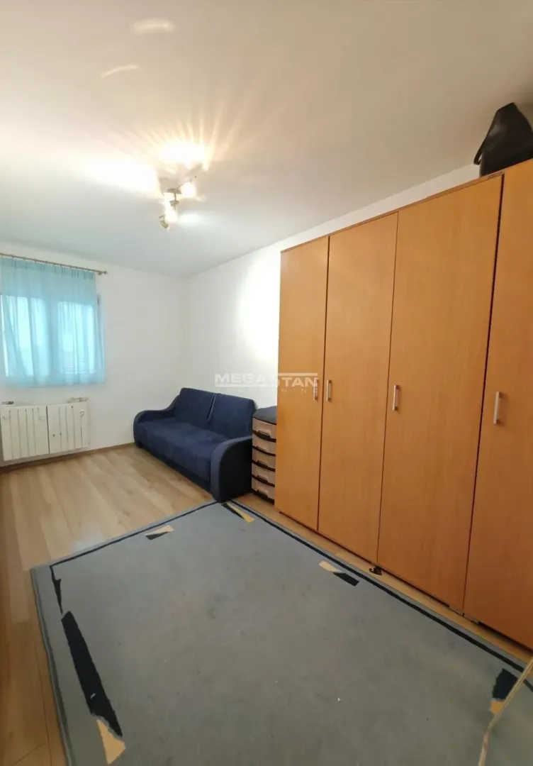 Spavaća soba sa velikim drvenim ormanom i kaučem.
