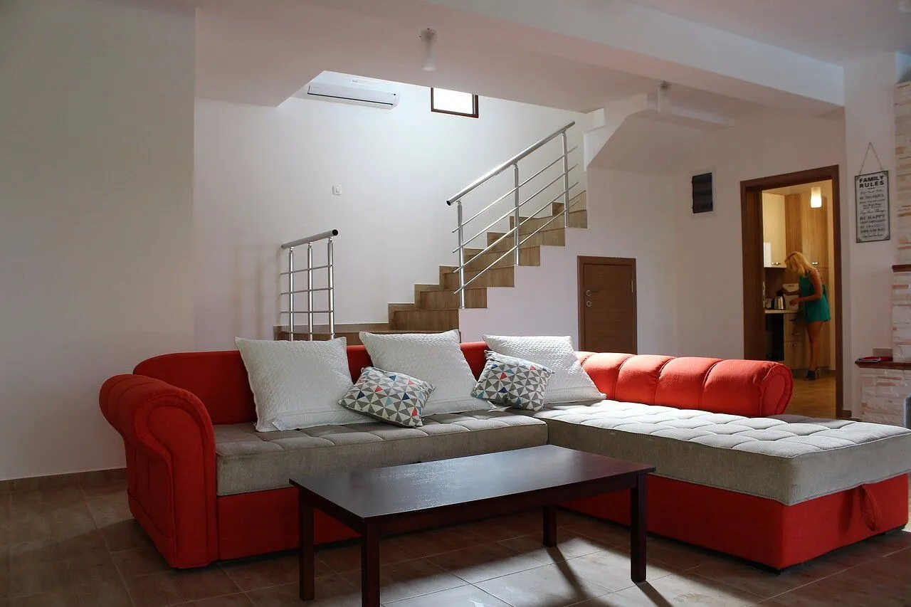 Living room with a red sectional sofa and stairs in the background.