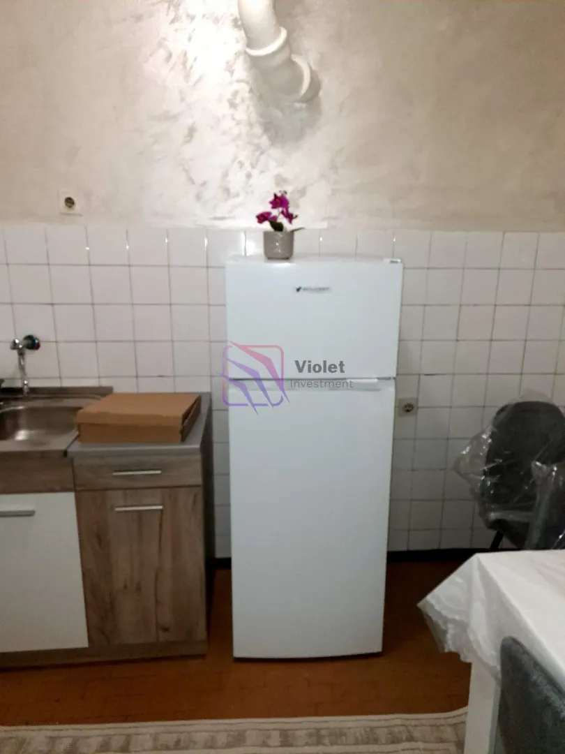 Small kitchen with a refrigerator, sink, and white tiles.