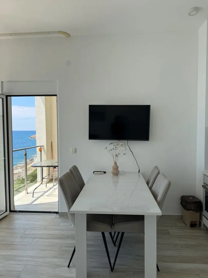 Dining area with a dining table and chairs, with access to a balcony overlooking the sea.