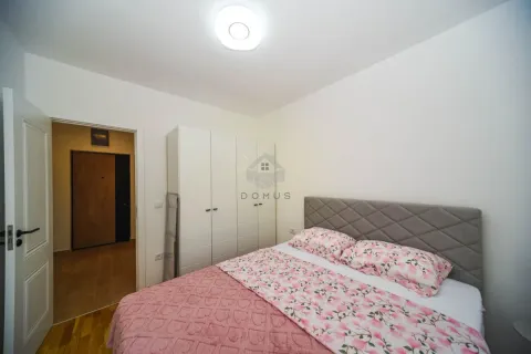 Namještena spavaća soba sa bračnim krevetom, bijelim garderoberom i ulaznim vratima u pozadini. - image 8