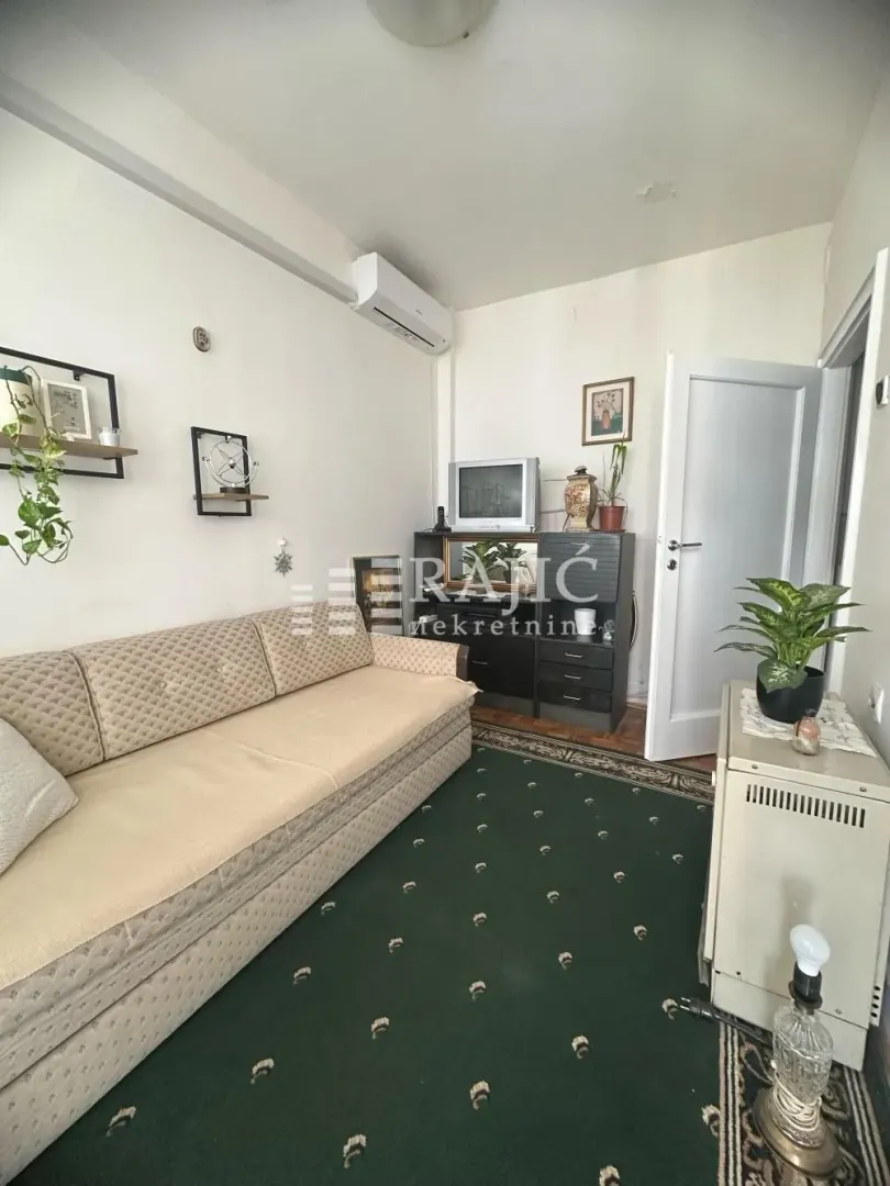 Small living room with a sofa and a green carpet.